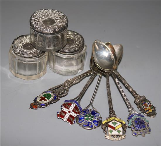 Three silver topped glass toilet jars and six silver and enamel commemorative spoons.